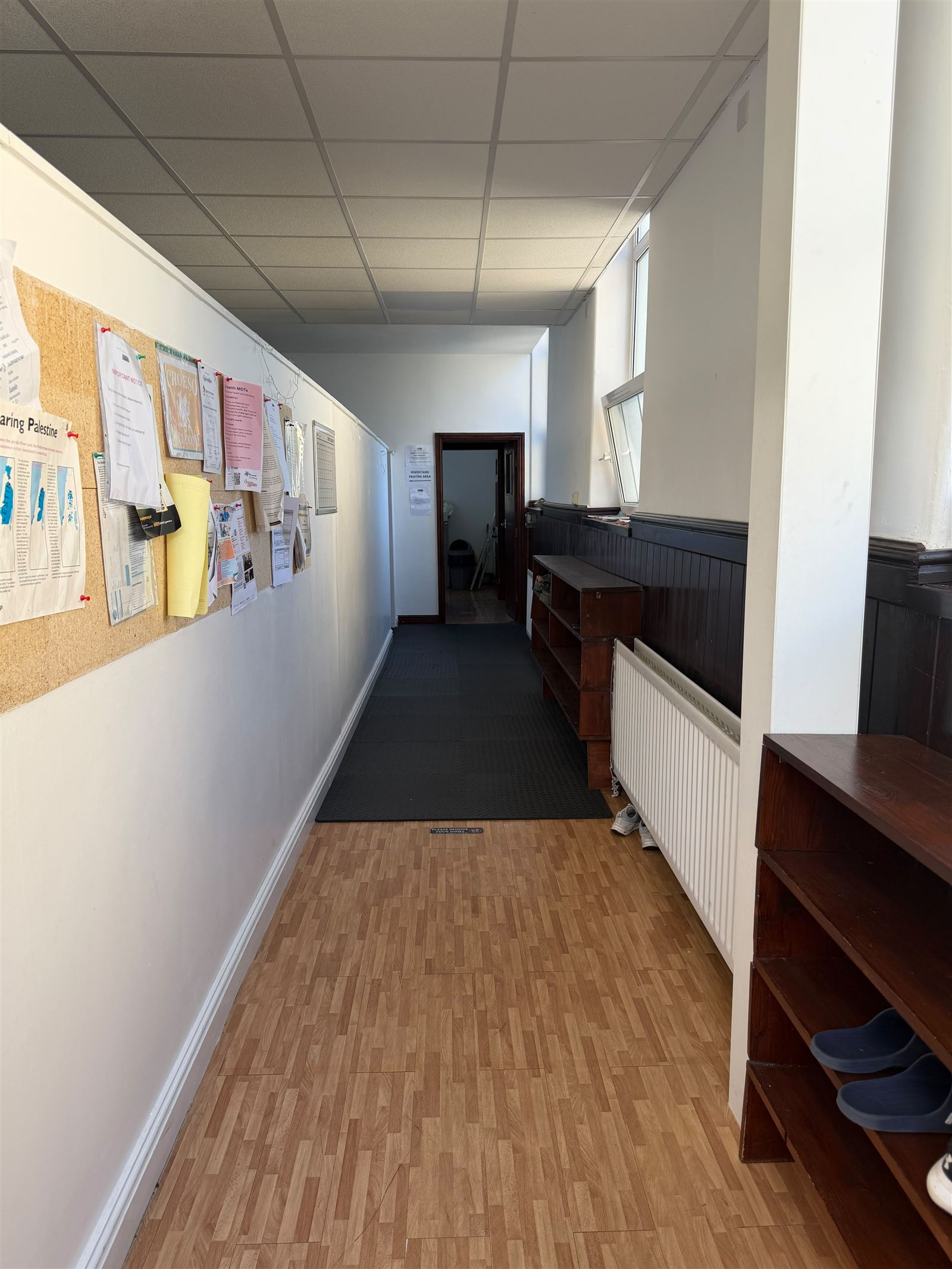 The entrance corridor at Canolfan Iman Centre, with shoe racks and noticeboard